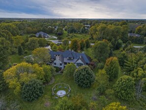 A large, multi-story house surrounded by lush greenery and a well-maintained lawn. - Baronwood Oasis | Pool + Arcade Mega Estate (Sheboygan)