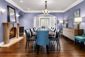 A dining room with a fireplace, a chandelier, and a view into the dining area. - Baronwood Oasis | Pool + Arcade Mega Estate (Sheboygan)