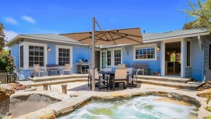 Une maison dotée d’un jacuzzi, d’un espace salon extérieur et d’un coin barbecue.