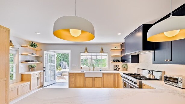 Une cuisine moderne avec des meubles en bois, un grand îlot central et des luminaires suspendus.