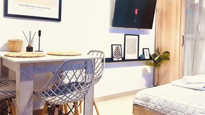 Une chambre à coucher moderne, avec un lit, un bureau et une chaise, un téléviseur fixé au mur et une armoire en bois.