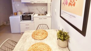 Une cuisine moderne avec des meubles blancs, un four à micro-ondes et un évier. Un tableau encadré est accroché au mur et une petite plante en pot est posée sur la table.