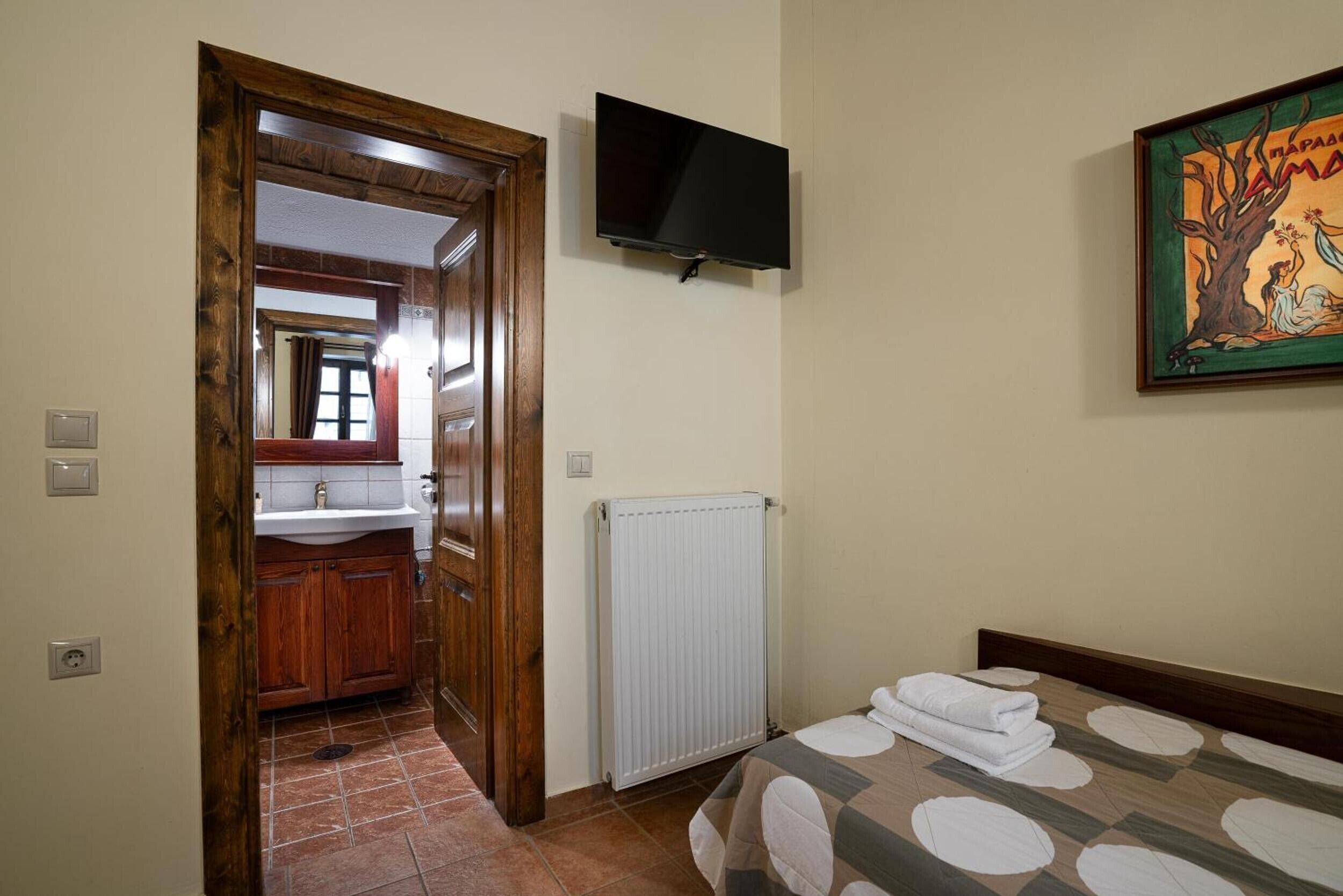 Une chambre à coucher avec un lit, une télévision, un radiateur et un tableau au mur.