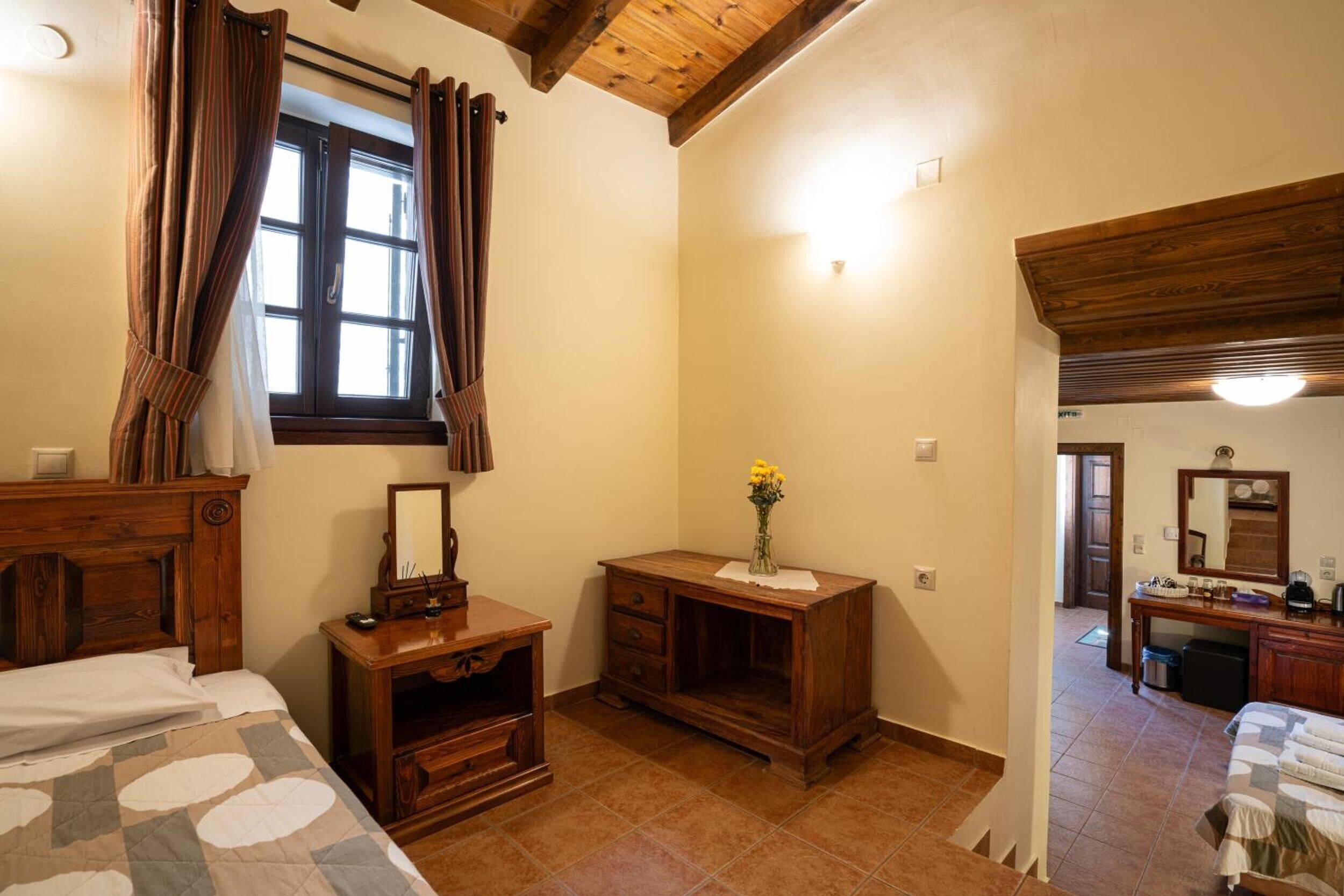 Ein Schlafzimmer mit einem Holz-Kopfteil, einem Nachttisch mit Spiegel, einer Kommode und einem Fenster mit Vorhängen.