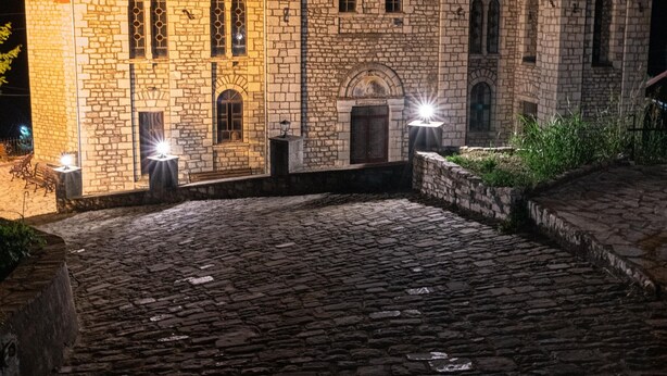 Ein mit künstlichem Licht beleuchtetes Gebäude aus Stein mit Kuppel und Glockenturm.