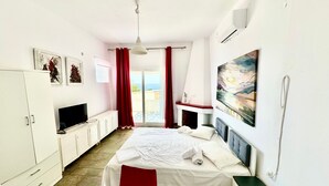 Un dormitorio con cama, televisor, armario, chimenea y un cuadro.