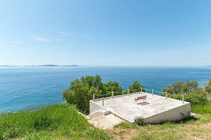 A concrete viewing platform with a bench, overlooking a body of water and distant land.