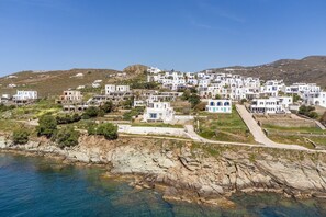 A coastal village with white buildings, rocky shoreline, and clear blue sea.