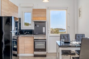 Une cuisine moderne équipée d’un réfrigérateur, d’un four et d’une cuisinière, un coin repas avec des chaises et une table, et une grande fenêtre offrant une belle vue.