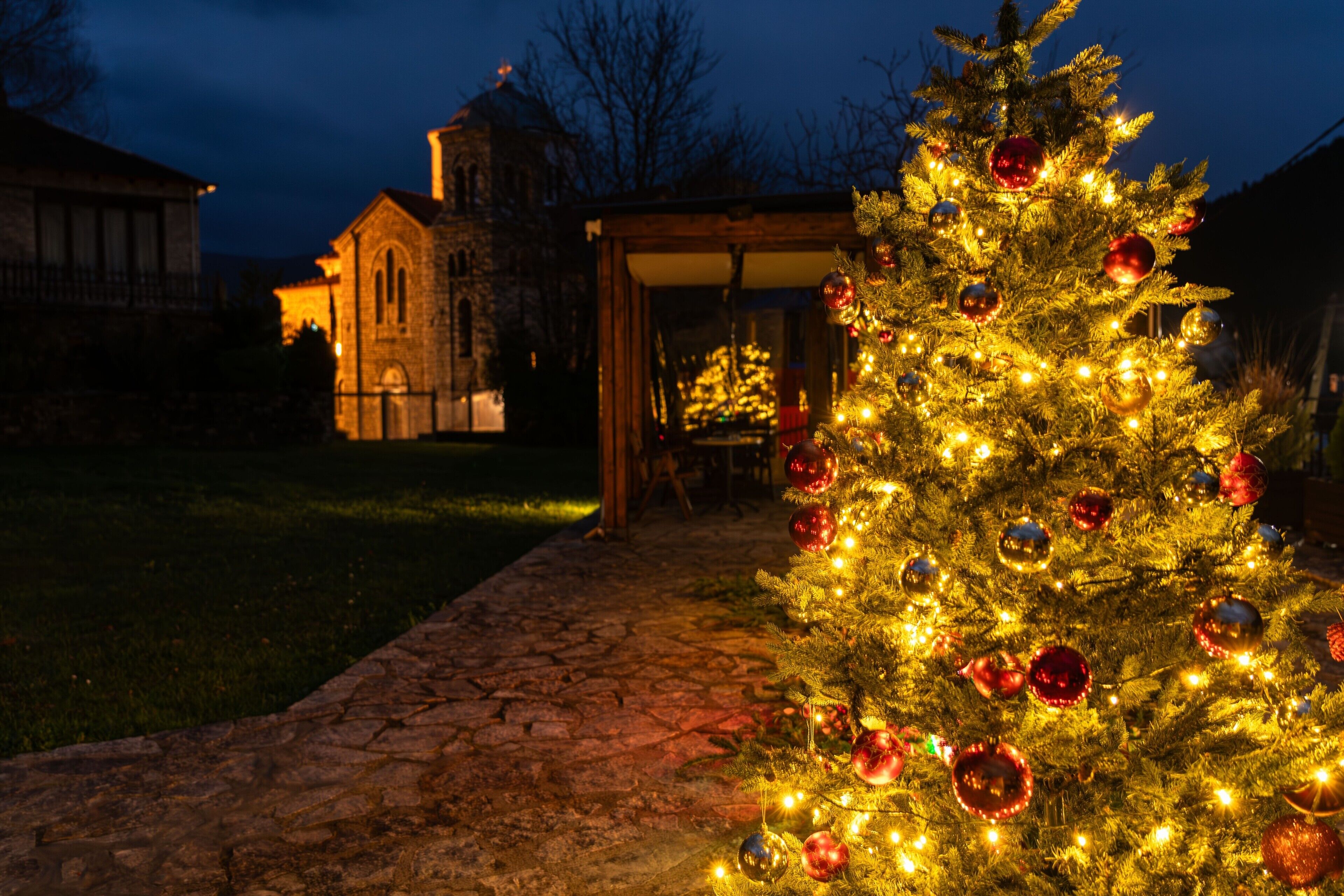 Ein Weihnachtsbaum mit Lichtern und Dekorationen vor einem Gebäude.