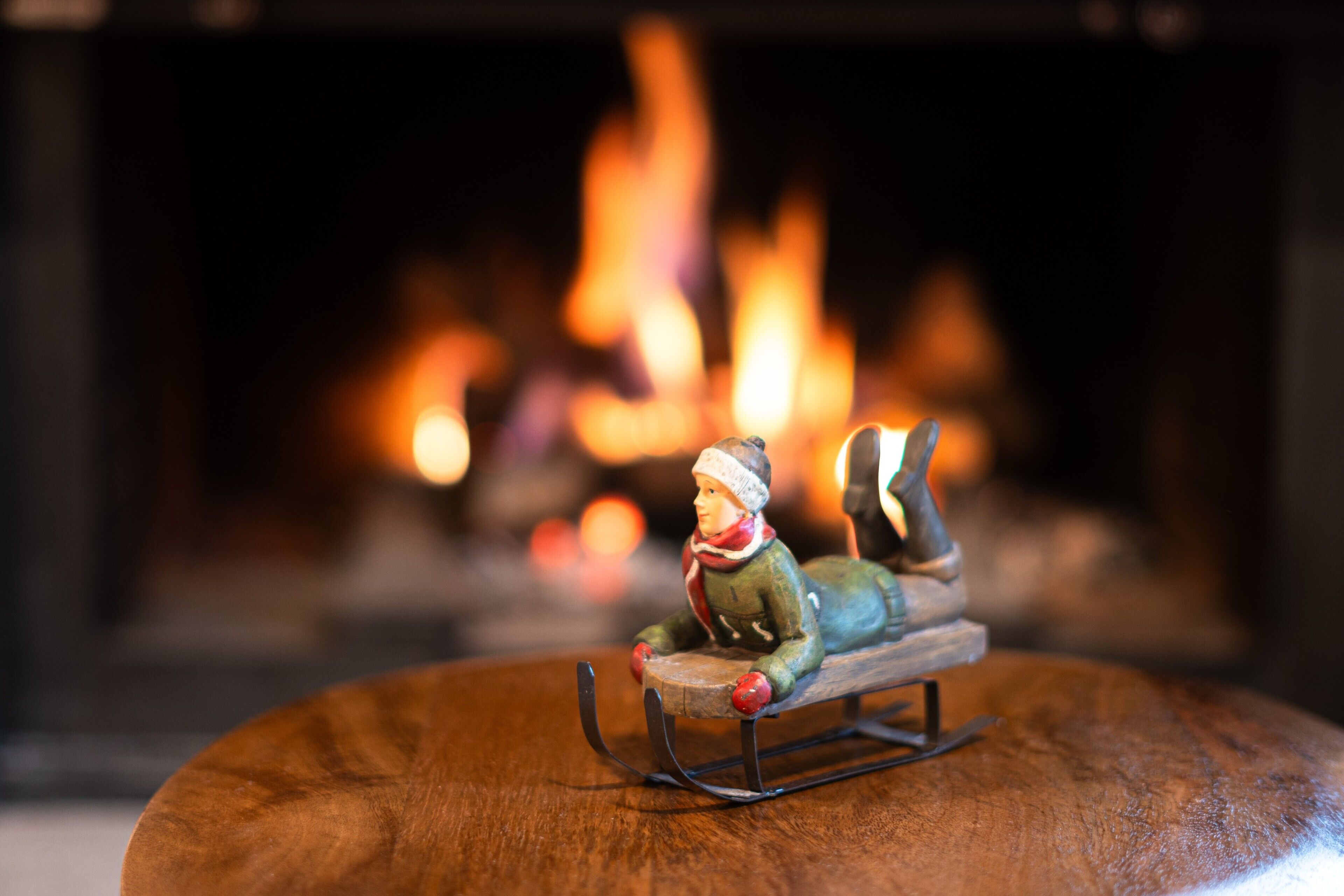 Une figurine représentant une personne sur une luge, devant une cheminée.