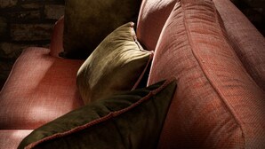 A room with a stone wall, a window with a view of outdoor furniture, and a red sofa with cushions. - Deluxe 'Dryopi' Apartment with Mountain View, Private Terrace & Wi-Fi (Karpenision)