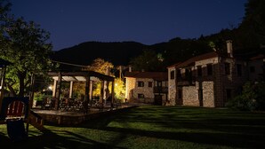 A stone building with a balcony, a covered patio area with tables and chairs, and a well-maintained lawn. - Deluxe 'Dryopi' Apartment with Mountain View, Private Terrace & Wi-Fi (Karpenision)