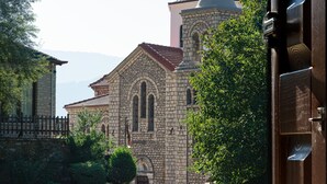 Un edificio de piedra con cúpula y ventanas de arco, rodeado de un muro de piedra y vegetación.