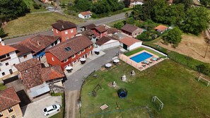 Oversigtsbillede af et boligområde med huse, en swimmingpool og en fodboldbane.