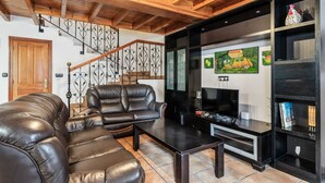 A living room with a leather sofa, a coffee table, a TV, and a bookshelf.