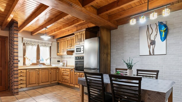 A kitchen with wooden cabinets, a dining table, and chairs.