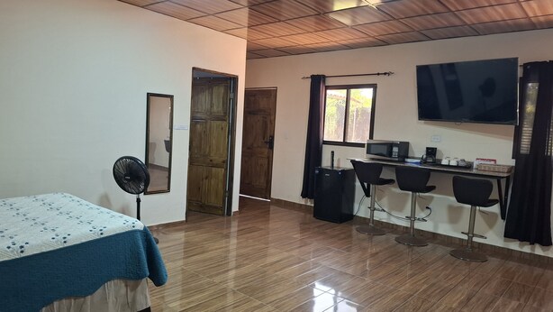 A room with a bed, a desk with a computer, a TV, and a fan. - PLEASANT HOSTAL PANAMA (24 de Diciembre)