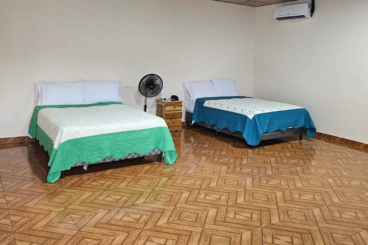 Une chambre avec deux lits, un ventilateur et un appareil de climatisation.