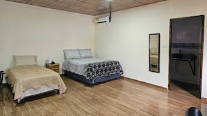 A bedroom with two beds, a ceiling fan, an air conditioning unit, and a mirror on the wall. - PLEASANT HOSTAL PANAMA (24 de Diciembre)