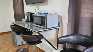 A small, modern room with a kitchenette, a flat-screen TV mounted on the wall, and a herringbone-patterned wooden floor. - PLEASANT HOSTAL PANAMA (24 de Diciembre)