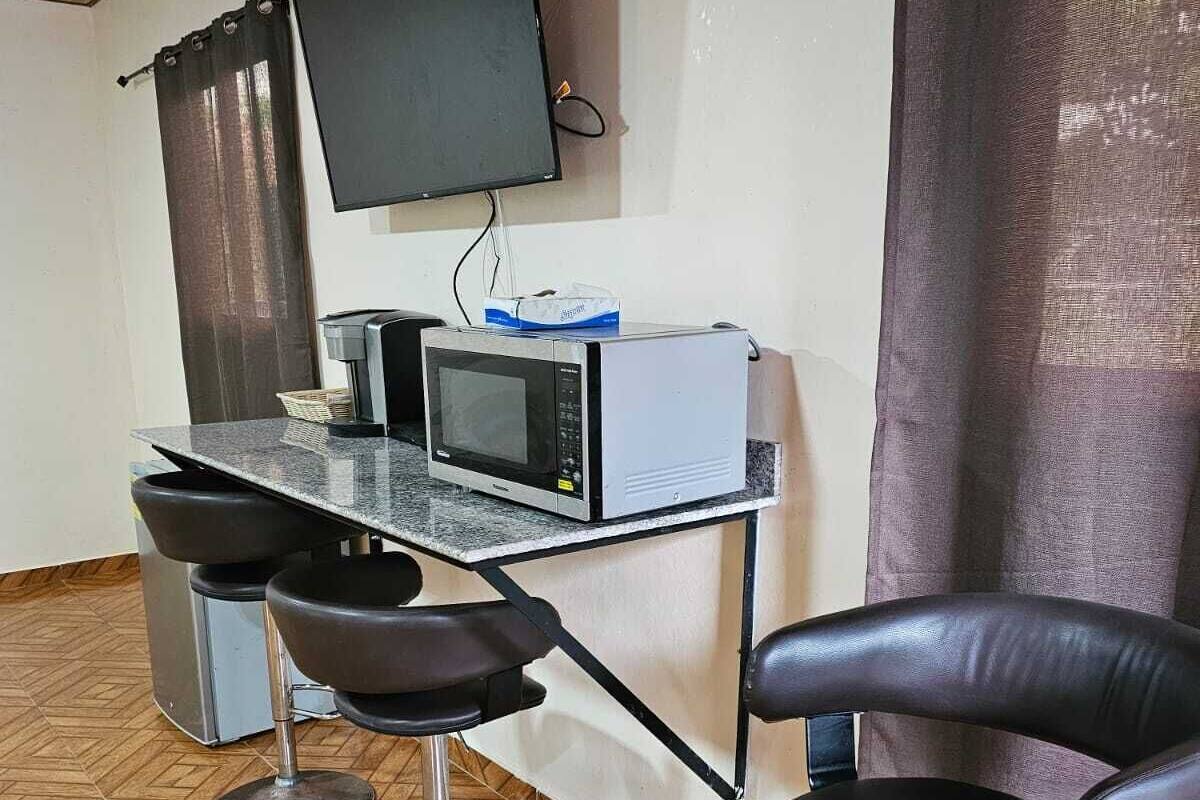 Une petite chambre moderne dotée d’une kitchenette, d’un téléviseur à écran plat fixé au mur et d’un parquet en bois disposé en motif chevrons.