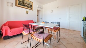 Un comedor con una mesa, sillas, un sofá rojo y un cuadro en la pared.