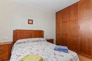 Un dormitorio con una cama de madera, una mesita de noche, un armario y un cuadro en la pared.