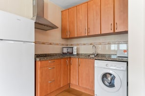 A kitchen with wooden cabinets, a microwave, a toaster, and a washing machine.