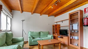 En stue med en grøn sofa, et træbord og et fjernsyn på et træskab.