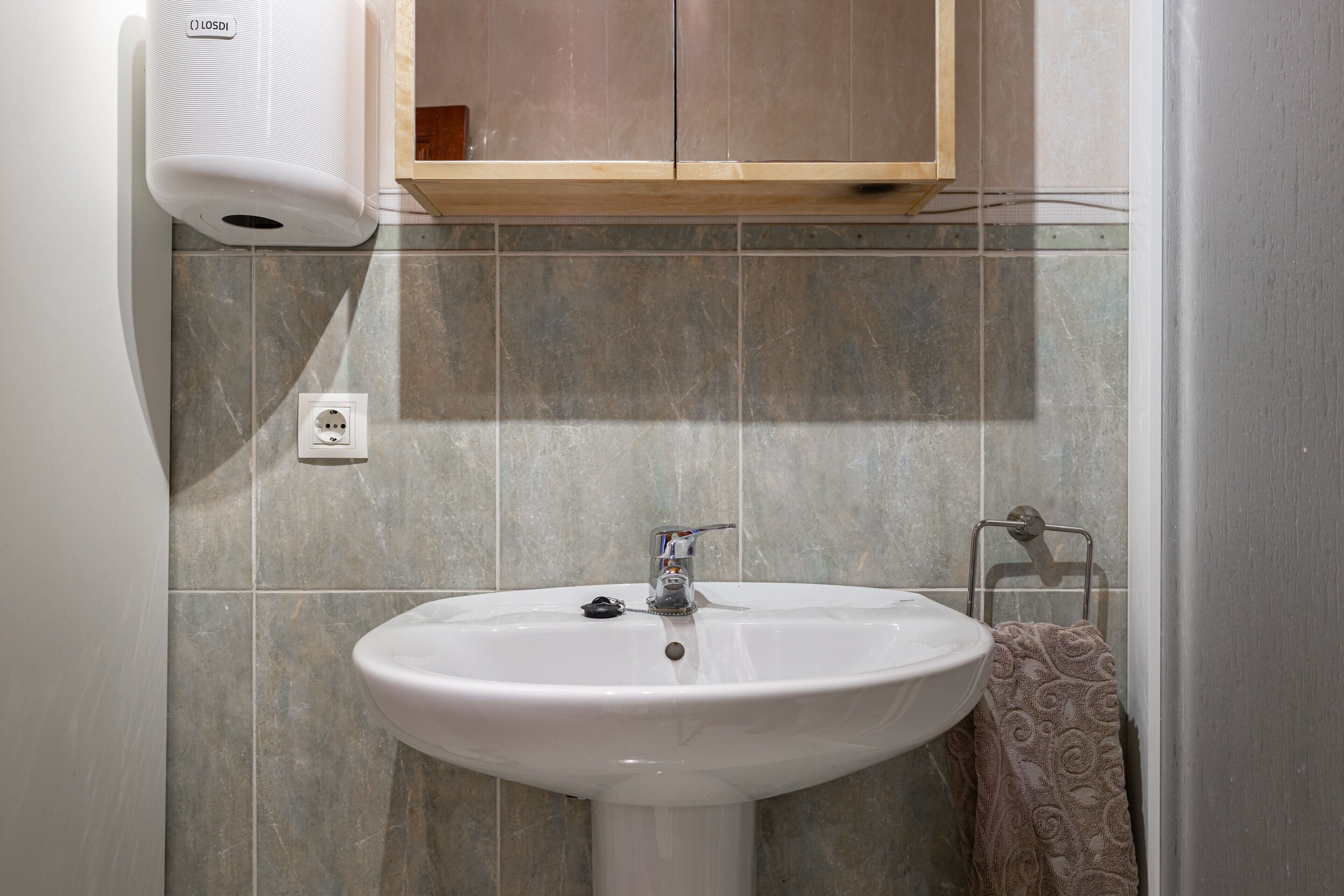 A bathroom with a white sink, a towel rack, and a hand dryer.