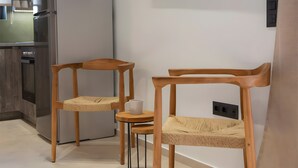 A modern kitchen with a built-in refrigerator, a small wooden table with chairs, and a wall-mounted television. - Studio 'Elfam City Suite B' with Shared Terrace, Wi-Fi and Air Conditioning (Lefkada Town)