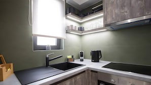 A kitchen with a black sink, a stove, and a window above the sink. - Studio 'Elfam City Suite B' with Shared Terrace, Wi-Fi and Air Conditioning (Lefkada Town)