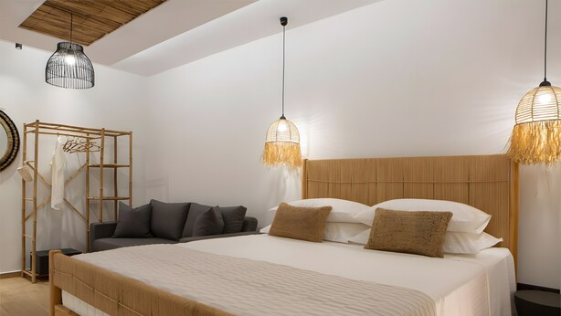 A modern bedroom with a large bed, wooden headboard, two hanging light fixtures, and a wooden bench. - Studio 'Elfam City Suite A' with Shared Terrace, Wi-Fi and Air Conditioning (Lefkada Town)