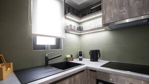 A kitchen with a black sink, a stove, and a window above the sink. - Studio 'Elfam City Suite A' with Shared Terrace, Wi-Fi and Air Conditioning (Lefkada Town)