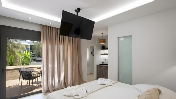 A modern hotel room with a bed, a TV, a desk, and a view of the outdoors.