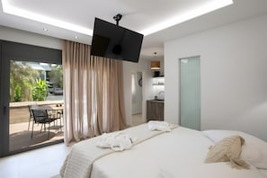 Een moderne hotelkamer met een bed, een televisie, een bureau en uitzicht op de omgeving.