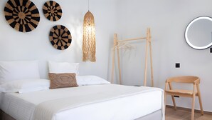 A bedroom with a bed, a wooden chair, a hanging light fixture, and wall-mounted circular mirrors.