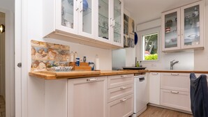 Una cucina con mobili bianchi, un piano di lavoro in legno e una finestra.