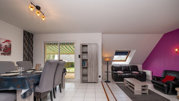 A modern living room with a dining area, a sofa set, a coffee table, and a bookshelf. - Holiday Home 'Entre Terre Et Mer' with Private Terrace, Garden & Wi-Fi (Pluvigner)