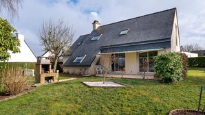 A house with a sloped roof, a chimney, and a garden with a lawn and a small tree. - Holiday Home 'Entre Terre Et Mer' with Private Terrace, Garden & Wi-Fi (Pluvigner)