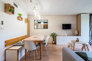 Un espace de vie moderne comprenant un coin repas, un canapé, un téléviseur et un coin cuisine.