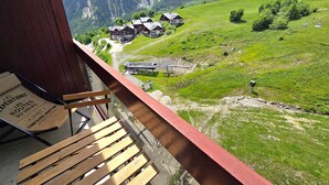 Vista de la montaña con un edificio de estilo chalé, terraza de madera y un letrero con texto.