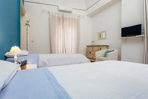 A hotel room with two beds, a dresser, a television, and a window with curtains. - Apartment 'The House In Baroque Style' with Wi-Fi and Air Conditioning (Catania)