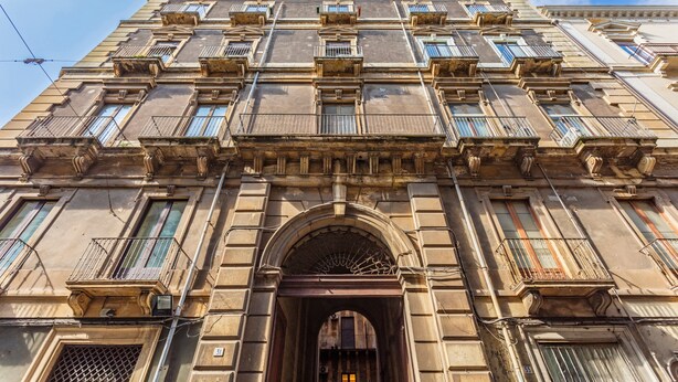 Un edificio de varios pisos con estilo arquitectónico clásico, que presenta una entrada central con arco, varios balcones y una serie de ventanas.