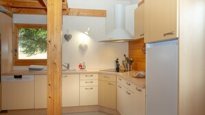 A kitchen with wooden cabinets, a dishwasher, a sink, and a window with a view of trees.