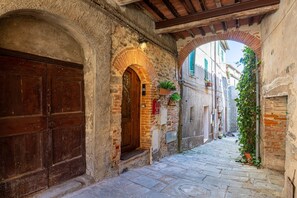 Un estrecho callejón empedrado con arcos y una puerta de madera.
