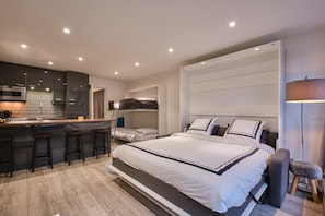 Een moderne slaapkamer met een groot bed, een inbouwkast en een kitchenette.