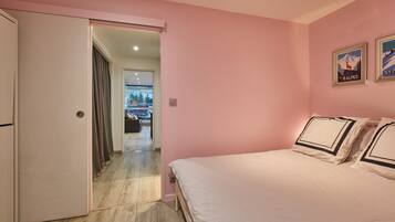 A bedroom with a bed, a door leading to another room, and a poster on the wall.
