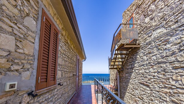 Ein Steinhaus mit einem Balkon mit Blick auf ein Gewässer.